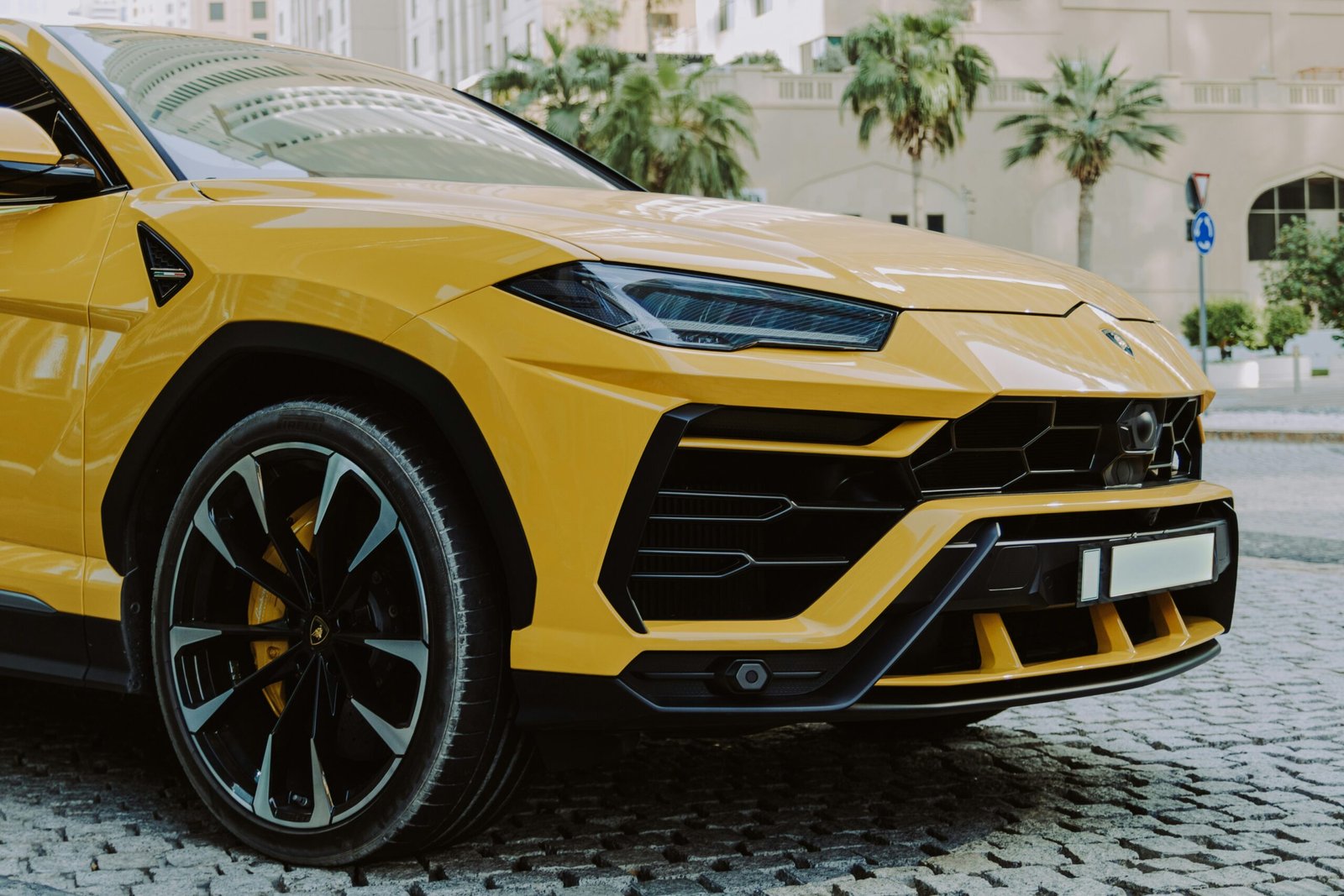 A yellow lamb suv parked on a cobblestone street